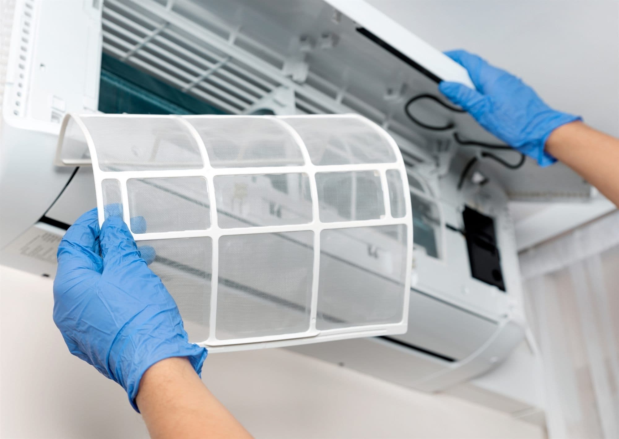 Technician cleaning an air-conditioning vent filter in a commercial space
